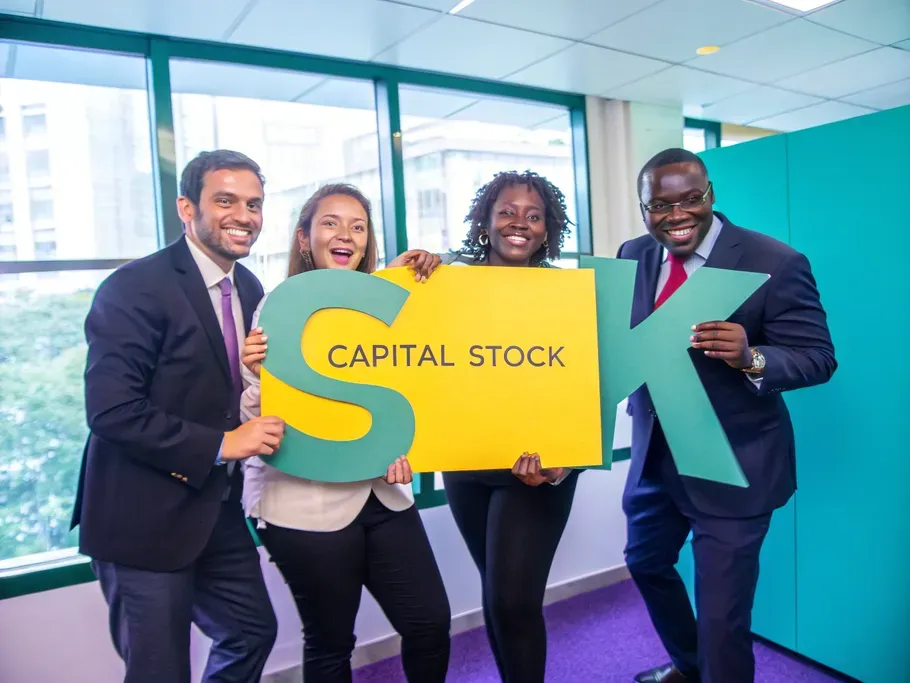 A diverse group of professionals in business suits holding colorful signs that say 'Capital Stock'.
