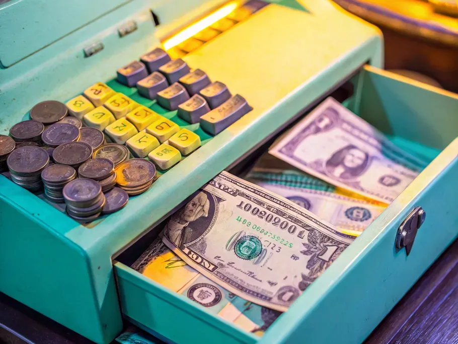 Vintage cash register with coins and dollar bills emphasizing sales discounts in accounting