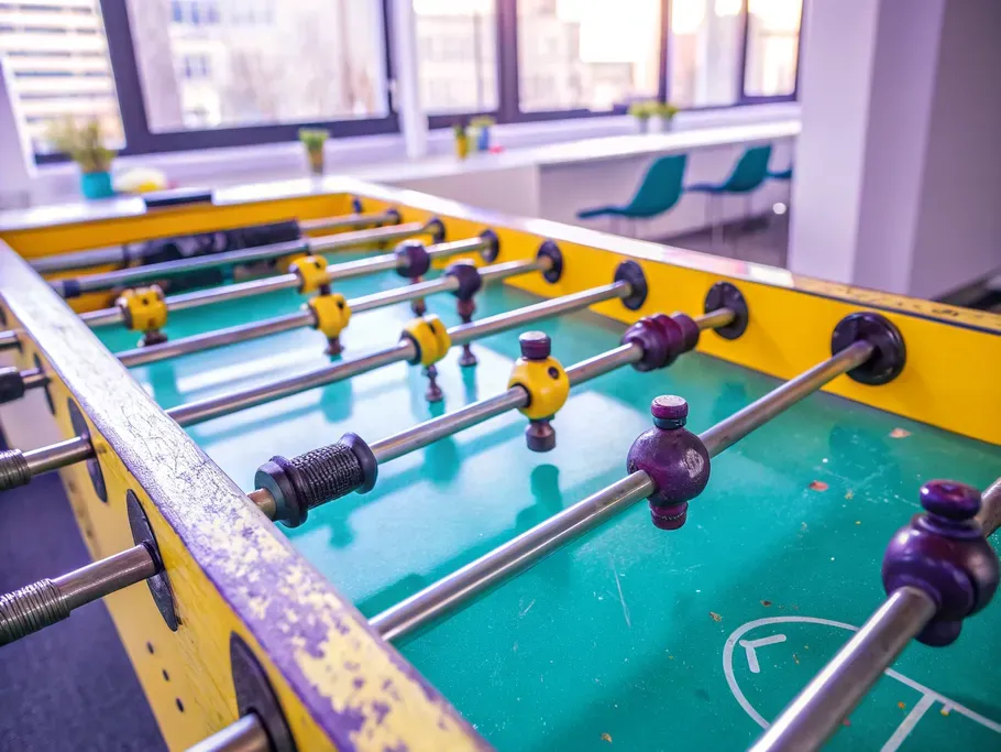 Brightly colored foosball table in an office game room with view of urban landscape through window