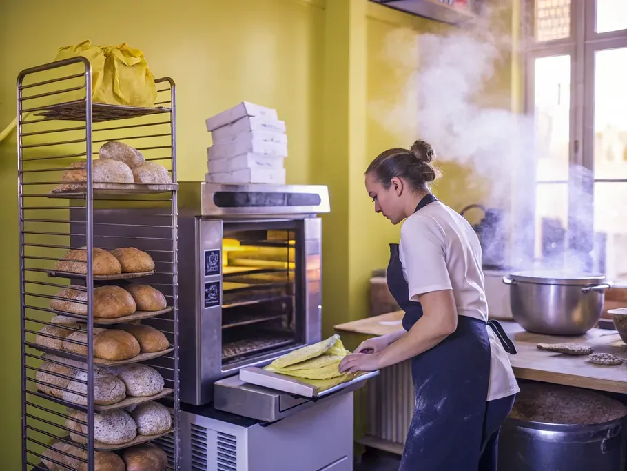 A passionate female baker examining a commercial oven in a cozy bakery interior.