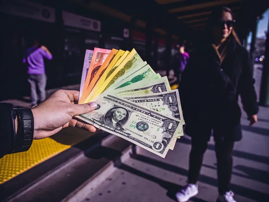 A hand holding a vibrant stack of American dollar bills, symbolizing financial transactions in accounting.