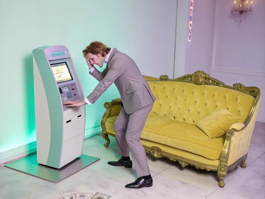 A distressed business person trying to insert a plush antique couch into a futuristic payment terminal.