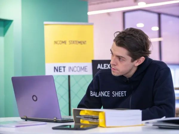A young founder examining financial documents at a modern desk, highlighting net income on an income statement and balance sheet.