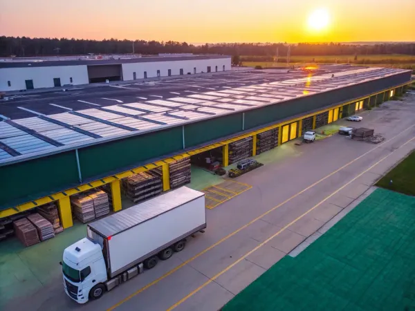 Aerial view of a modern warehouse facility with organized inventory and a delivery truck at sunset.